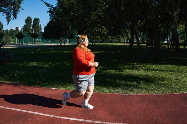 A cheerful woman exercises outdoors, embracing fitness in nature.
