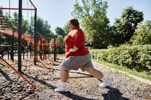 A beautiful plus size woman focuses on her stretches outdoors.