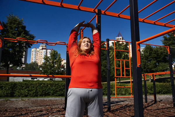 Woman stretches joyfully under clear blue skies in a lively park setting.