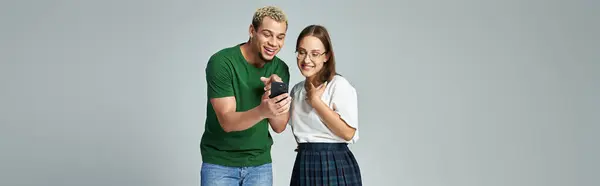 stock image Two friends share laughter while engaging with a smartphone.