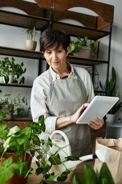 A gardener tends to her thriving plants with a tablet in hand. clipart