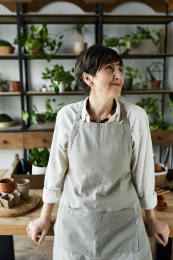 Olgun bir kadın, yaratıcı alanında sevdiği bitkilerle neşeyle ilgilenir..