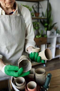 Bir bahçıvan bitkileriyle ilgilenirken tencere düzenler..