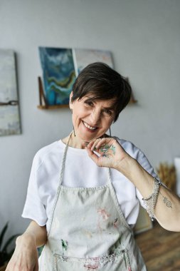 Olgun kadın coşkulu stüdyosunda sanat yaparken neşe saçıyor..