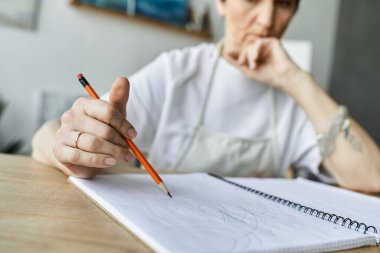 Olgun bir kadın, rahat sanat stüdyosunda resim çizerken konsantre olur..