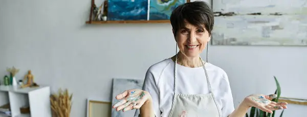 Stock image A mature woman joyfully expresses her creativity in her art studio.