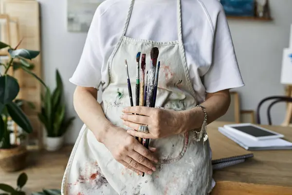 stock image A skilled painter joyfully embraces her tools in a bright art studio.