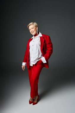 Yetişkin bir kadın, çarpıcı bir kırmızı elbiseyle sofistike bir moda sergiliyor..