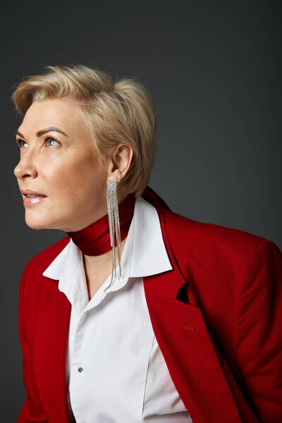 Стильная женщина в элегантном красном наряде смотрит вверх, источая уверенность и изящество.