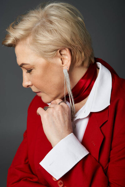 Шикарная женщина носит красный пиджак и аксессуары, излучая изысканность.