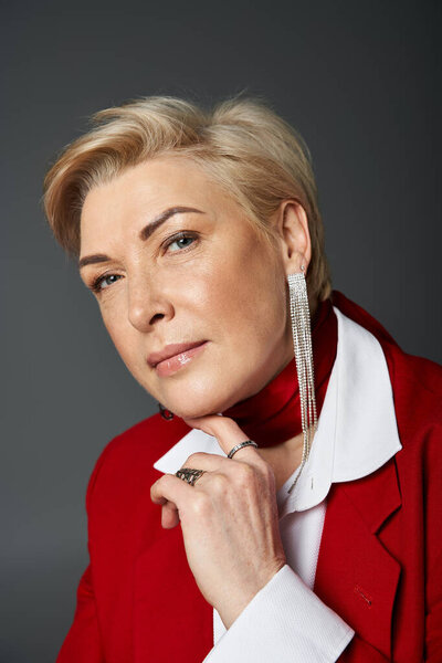 Взрослая женщина, элегантно одетая в красное, излучает очарование и изысканность в своей позе..