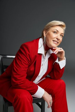 Zarif bir kadın, parlak kırmızı elbiseler giyer. Oturur ve izleyiciyle yakınlaşır..