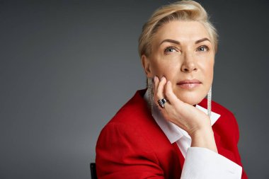 Kırmızı giyinmiş yetişkin bir kadın çağdaş bir uzayda düşünceli bir şekilde düşünür..