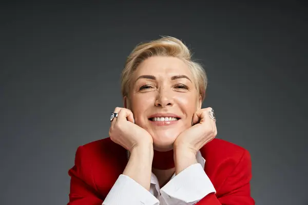 Stock image A stylish woman radiates confidence and joy while resting her chin on her hands.