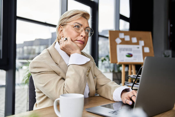 Модная женщина размышляет, работая за своим современным рабочим столом.