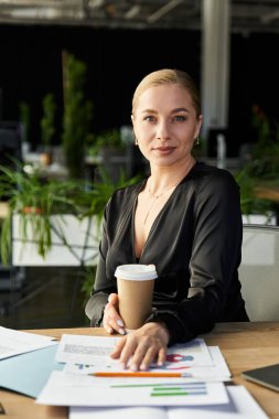 Genç, güzel, iri yarı bir kadın elinde sıcak bir kahveyle ofisteki görevlerine odaklanıyor..
