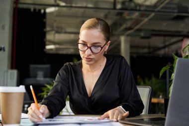 Genç, güzel ve iri yarı bir kadın hayat dolu bir ofis ortamında çalışıyor..