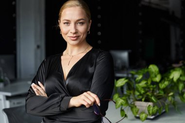 Genç, güzel, iri yarı bir kadın bir ofis ortamında kendine güvenerek duruyor. İşiyle meşgul..