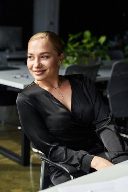 Kendinden emin genç ve iri yarı bir kadın modern bir ofiste işine odaklanmış durumda..