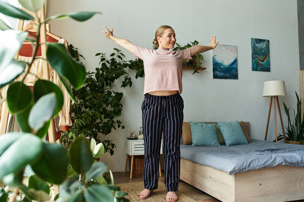 Молодая красивая женщина плюс размер простирает руки широко, наслаждаясь спокойным моментом дома.