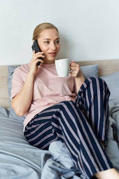 A young plus size woman relaxes at home, sipping coffee and chatting on the phone.