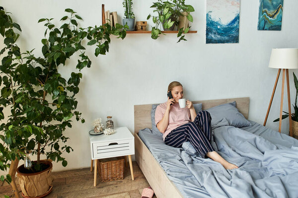 Молодая, красивая плюс размер женщина пьет чай и расслабляется в спокойной, растительной заполненной комнате.