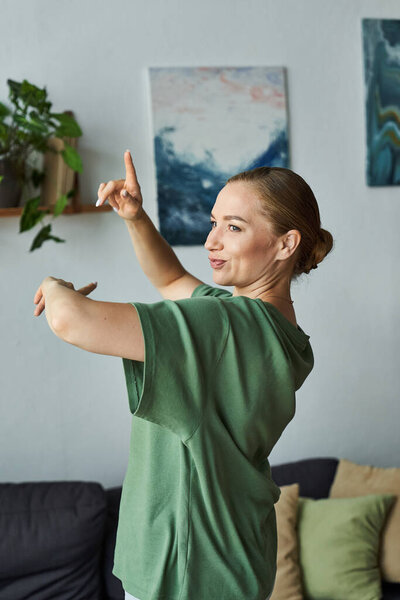 A joyful plus size woman dances at home, expressing herself in a vibrant atmosphere.