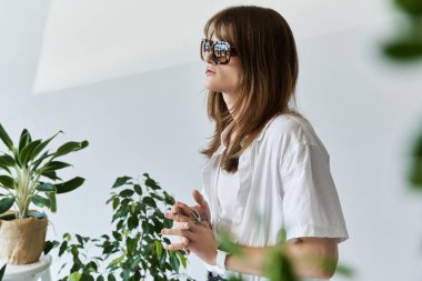 Modern bir mekanda yemyeşil bir çevresi olan şık bir genç adam düşünceli bir şekilde ayakta duruyor..