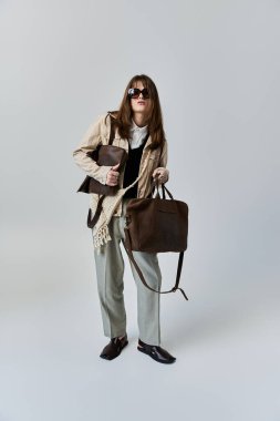 Şık giyinmiş genç bir adam kendine güvenerek poz verir, şık bir yerde şık çantalar taşır..