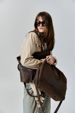 Bu genç, modaya uygun kişi, çeşitli çantalar taşıyor, şehir kıyafetlerine güven ve tarz yayıyor..