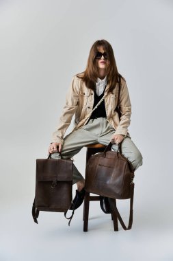 Modaya uygun bir birey modern giysiler sergilerken şık çantalarla cesur bir poz veriyor..