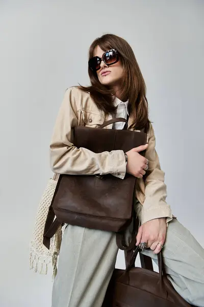 stock image A fashionable young man poses confidently with stylish outfits and sleek bags in a studio.