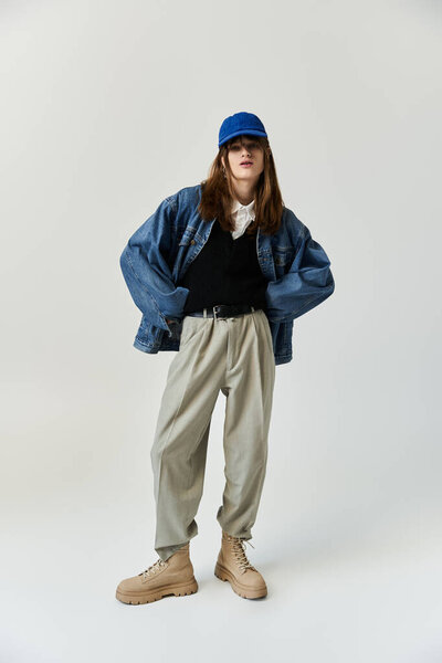 Молодой человек демонстрирует свой модный наряд и отношение в чистом, ярком пространстве.