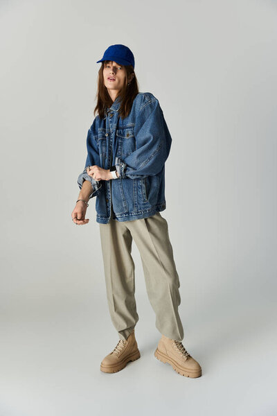 Молодой человек излучает стиль в модном наряде, уверенно позируя в минималистской студии.