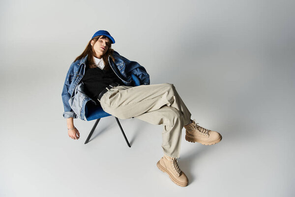 Молодой человек в модной одежде расслабляется на стуле, излучая уверенность и стиль.