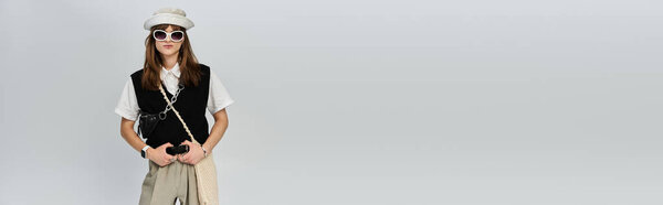 Молодой парень, одетый в модный наряд, уверенно стоит в чистом современном пространстве.