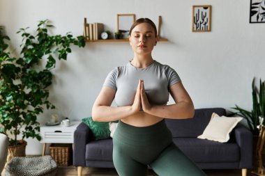 Genç bir kadın evde özenli bir egzersiz yapıyor, fitness 'e olan bağlılığını gösteriyor..