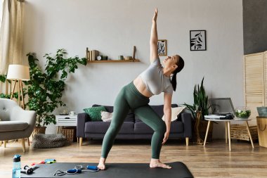 A young woman in stylish active wear performs a dynamic stretch in her inviting living space, energizing her day. clipart