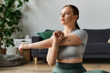 Genç bir kadın spor yapıyor, spor yaparken kollarını uzatıyor spor olsun diye..