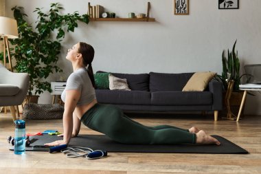 A sportive woman engages in a home workout, stretching and enhancing her flexibility in active wear. clipart