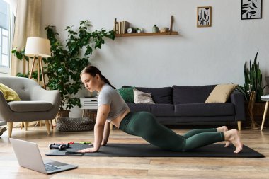 Kırpılmış bluzlu ve taytlı genç bir kadın spor yapıyor, spor salonuna odaklanıyor..