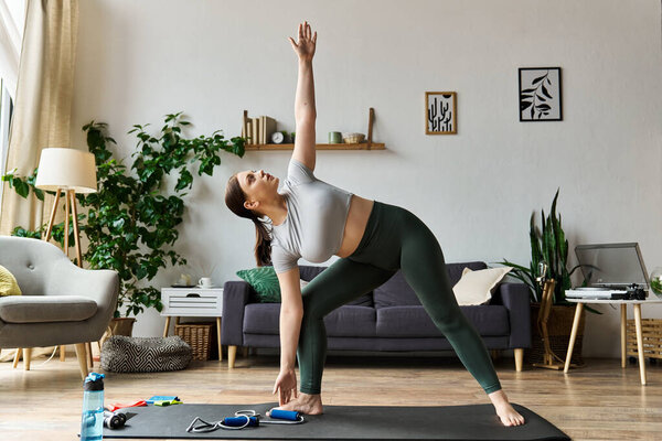 Молодая женщина практикует йогу дома, одетая в топ и леггинсы, фокусируясь на тренировках.