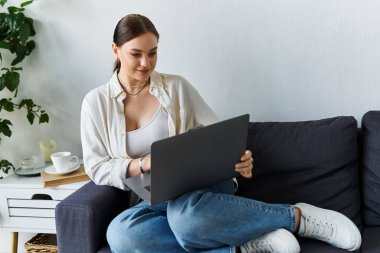 Genç bir kadın rahat bir şekilde koltuğunda oturur, etrafı sakin bir ofis ortamıyla çevriliyken işine odaklanır..