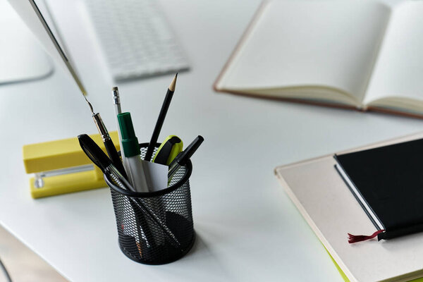 A young woman works diligently in her cozy home office, surrounded by her tools and a computer monitor.