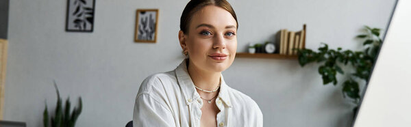 Молодая женщина в стильной повседневной одежде фокусируется на своих задачах, работая из дома в яркой обстановке.