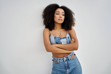 Kendine güvenen genç bir Afrikalı Amerikalı kadın modaya uygun kot pantolon içinde parlıyor ve tarzını sergiliyor..