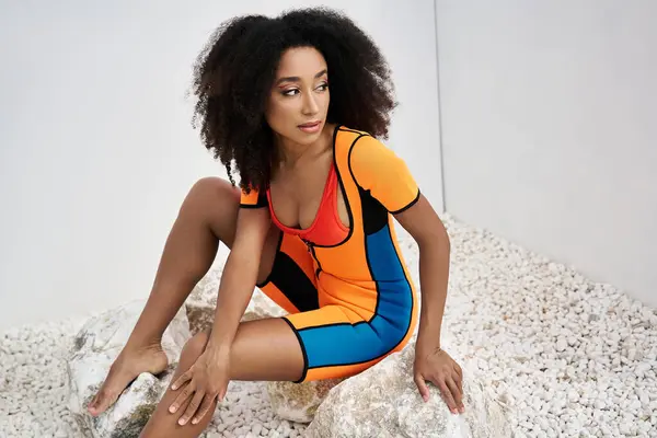 stock image A stylish young woman showcases her colorful outfit while posing gracefully amidst rocks.