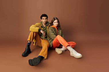 A stylish couple dressed in vivid autumn attire poses together in warm tones, exuding charm. clipart