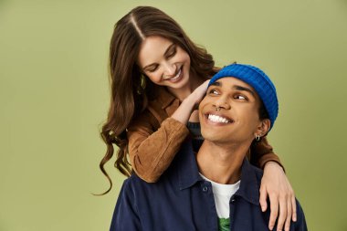 Genç bir çift, neşeli bir arka plana karşı kahkahalarını ve modaya uygun sonbahar kıyafetlerini paylaşıyor..