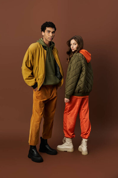 A fashionable couple showcases vibrant autumn outfits, exuding cozy charm in a warm setting.